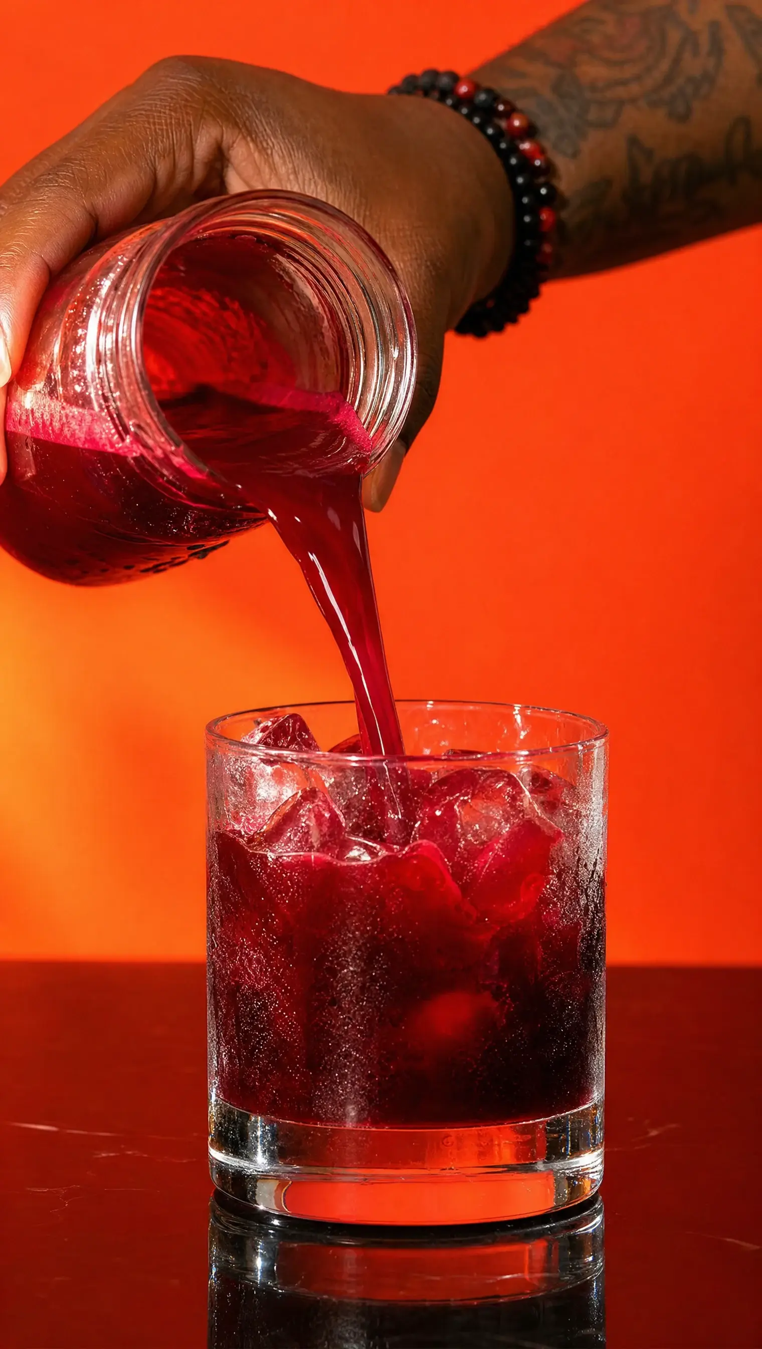deep red beet juice being poured over ice against an orange background